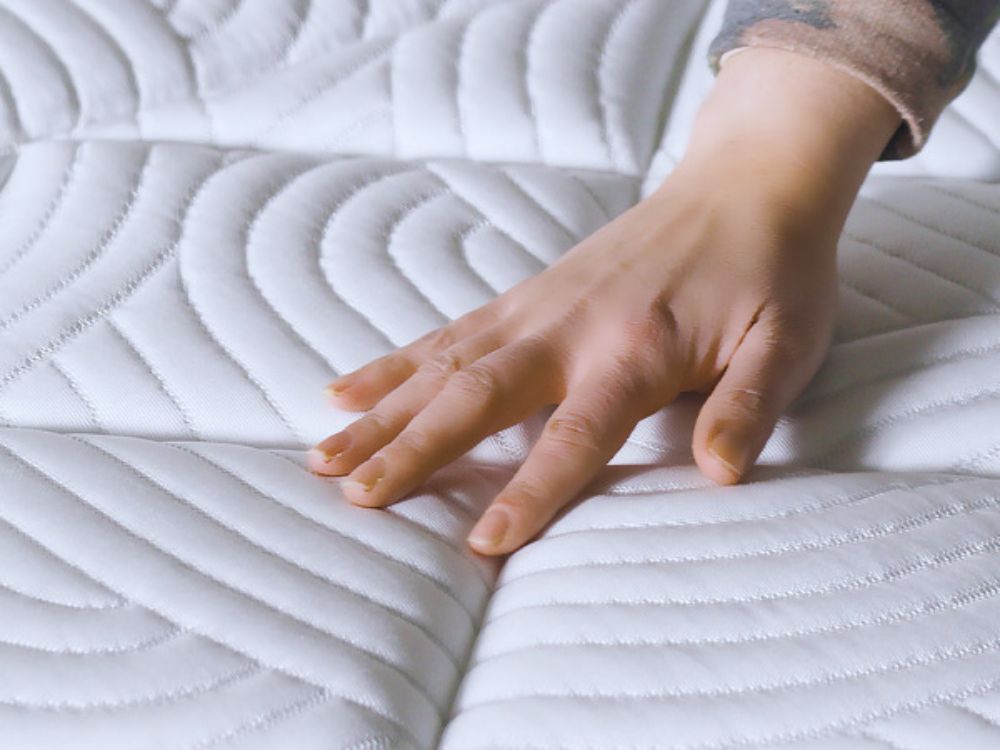 Mano tocando el tejido fresco de los colchones KHAMA