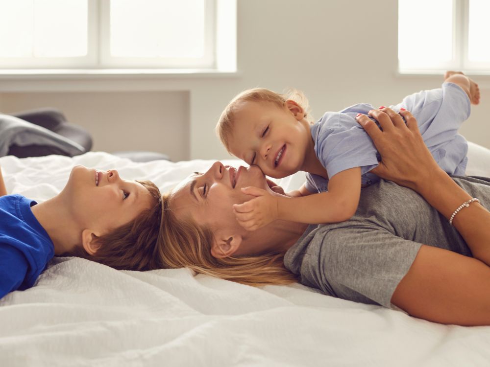 Una madre y sus hijos tirados en la cama celebrando el Día de la Madre